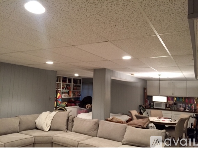 A living room with a grey couch and a kitchen area in the background.