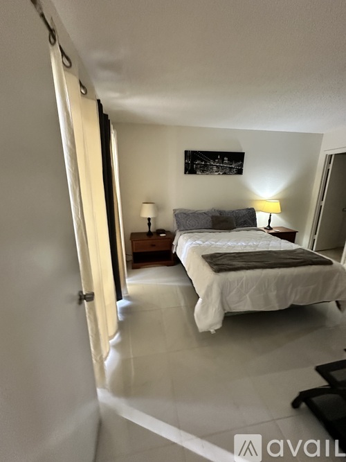 A bedroom with a bed, two lamps, and a painting on the wall.