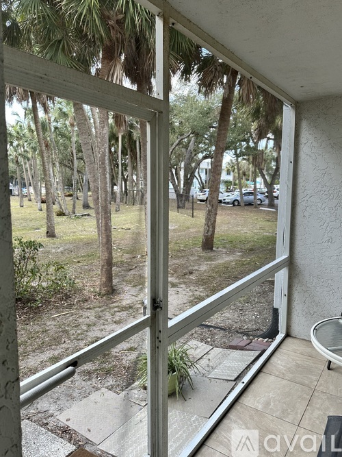 A balcony with a view of a grassy area and trees.