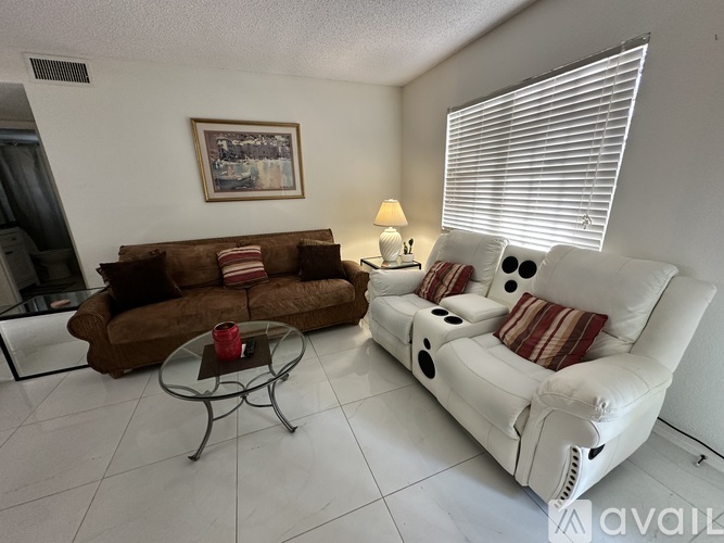 A living room with a white couch and a brown couch.