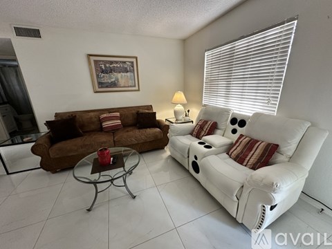 A living room with a white couch and a brown couch.