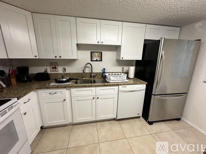 A kitchen with white cabinets and a stainless steel refrigerator.