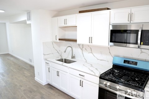 A kitchen with white cabinets and a black stove top oven.