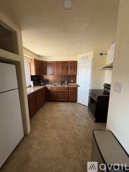 A kitchen with brown cabinets and a white refrigerator.