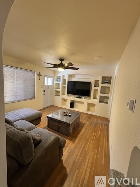 A living room with a grey couch and a wooden floor.