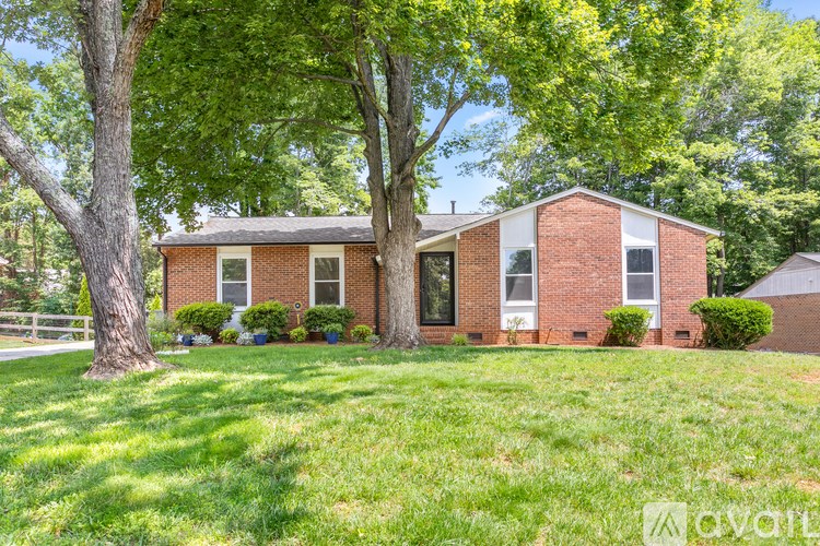 A house with a green lawn and trees in front.