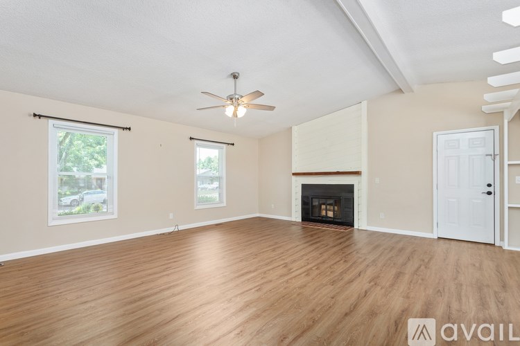 A spacious room with a fireplace and wooden flooring.