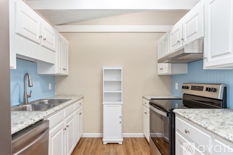 A kitchen with white cabinets and a blue backsplash.