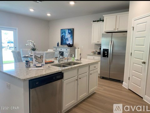 A kitchen with white cabinets and a stainless steel refrigerator.