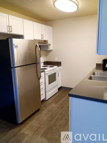 A kitchen with a black refrigerator and white cabinets.
