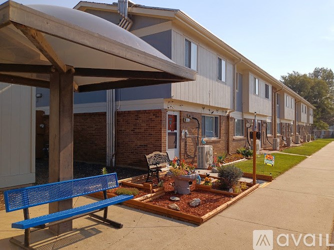 A blue bench is in front of a building with a planter box in front of it.
