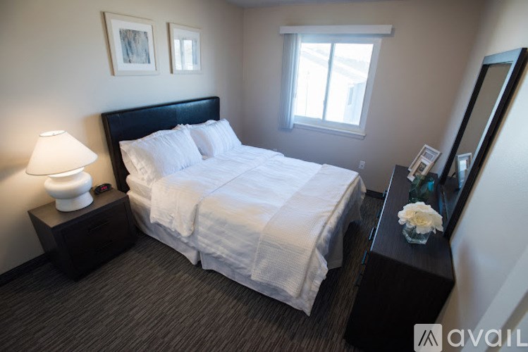 A bedroom with a large bed, a nightstand with a lamp, and a mirror.