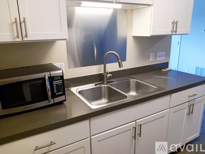 A kitchen with a microwave, sink, and cabinets.