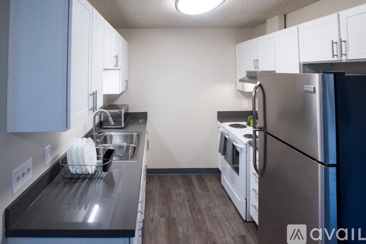 A kitchen with a refrigerator, oven, and sink.