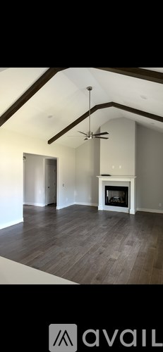 A spacious living room with a fireplace and a ceiling fan.