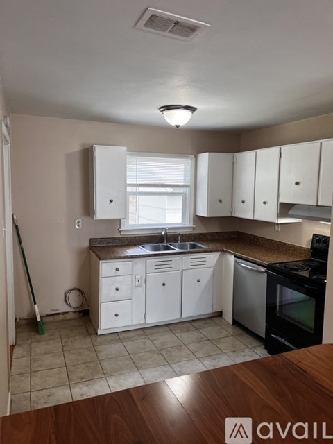 A kitchen with white cabinets and a wooden counter.