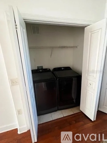 A small kitchen with two black fridge-freezers in it.