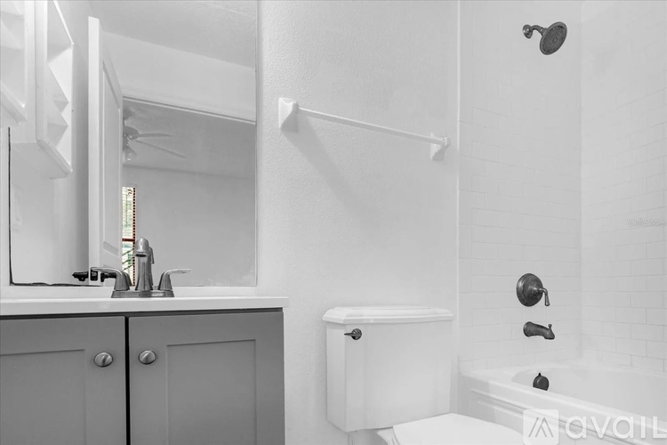 A white bathroom with a sink, mirror, and bathtub.