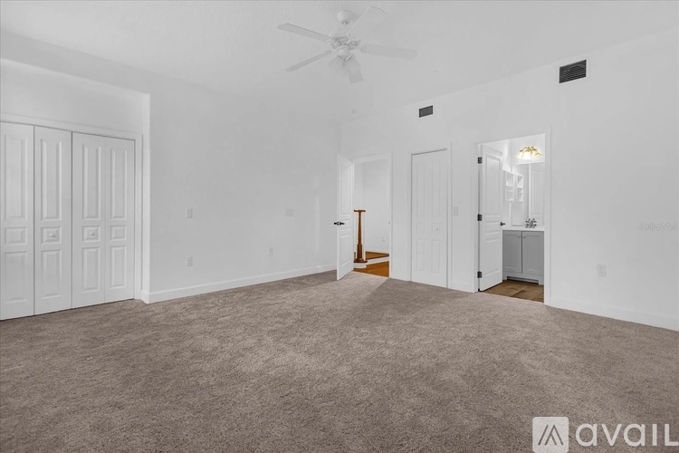 A spacious room with a carpeted floor and a ceiling fan.