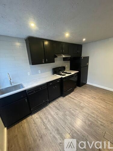 A kitchen with black cabinets and a wooden floor.