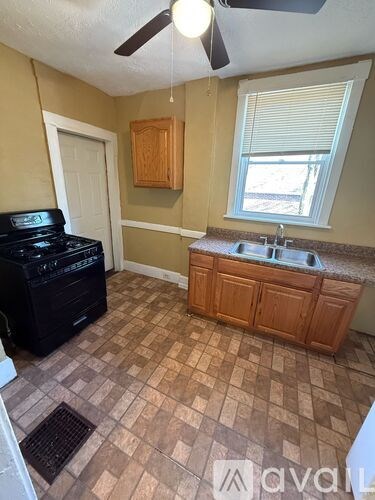 A kitchen with a black stove top oven and a brown tiled floor.