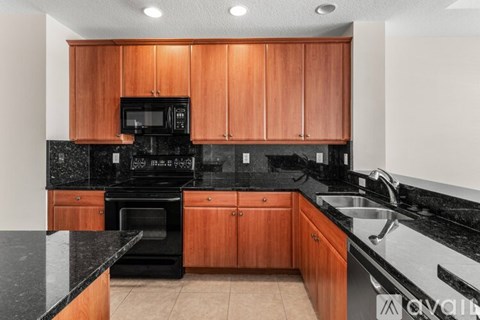 A kitchen with wooden cabinets and black countertops.
