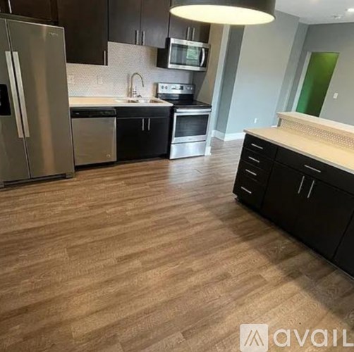 A kitchen with a refrigerator, microwave, oven, and sink.