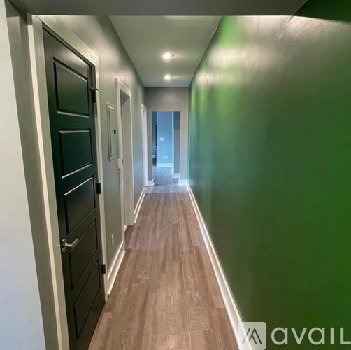 A long hallway with green walls and wood flooring.