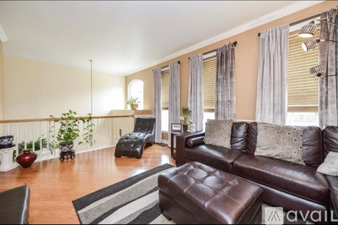 A living room with a brown leather couch and a striped rug.