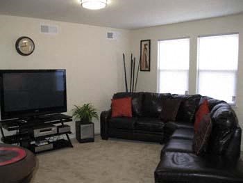 a living room with a black leather couch and a television