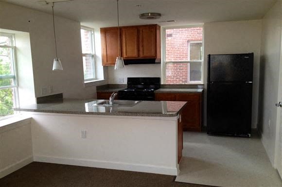 an empty kitchen with a black refrigerator and a sink