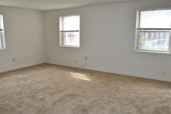 an empty room with two windows and a carpeted floor