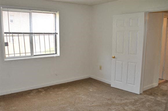 an empty room with a white door and a window