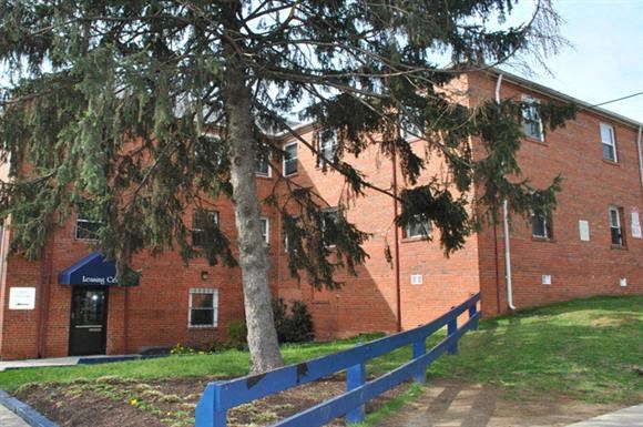 a brick building with a blue fence and a tree