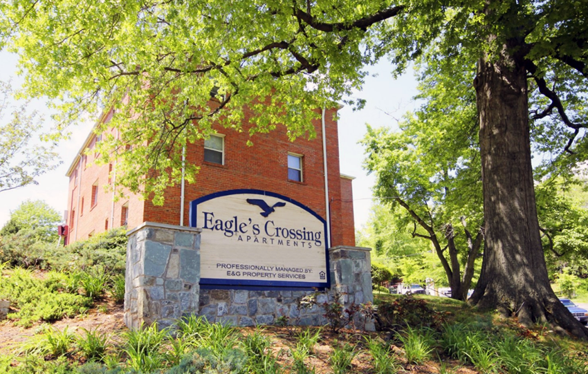 a sign for eagle crossing apartments in front of a tree