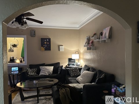 A living room with a black couch and a ceiling fan.