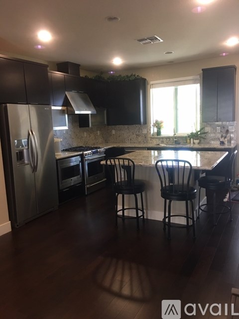 A kitchen with black cabinets and a stainless steel refrigerator.
