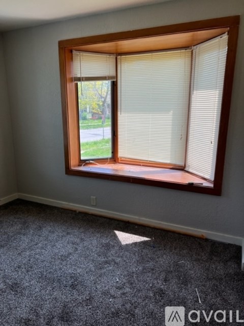 A room with a carpeted floor and a window with blinds.
