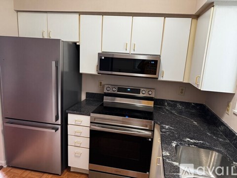 A kitchen with a refrigerator, microwave, and oven.