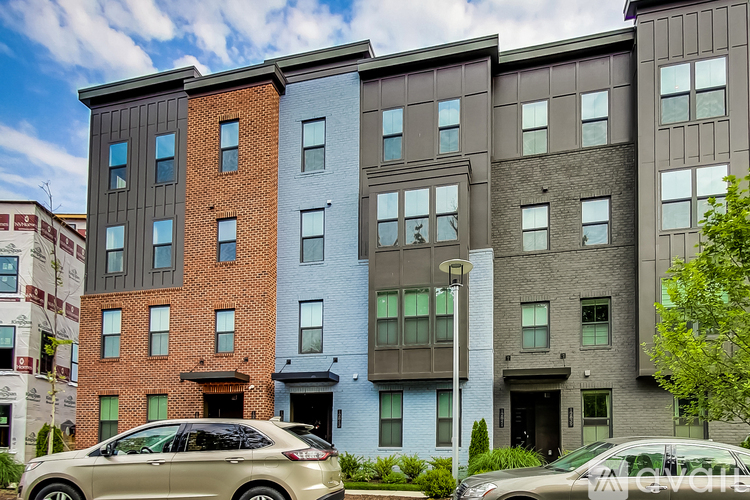 A row of modern apartment buildings with cars parked in front.