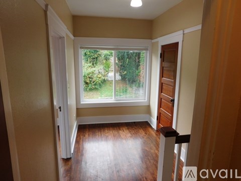 A room with a large window and wooden floors.