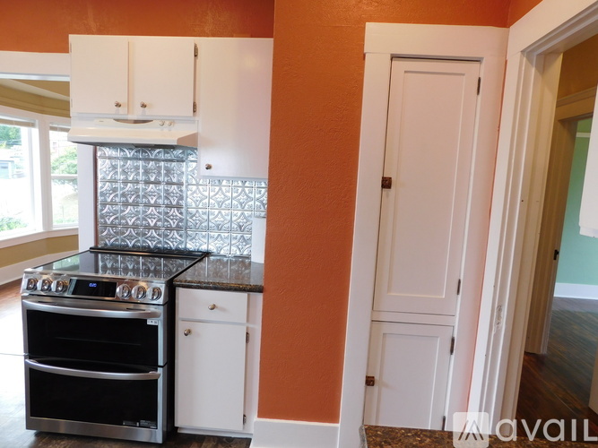A kitchen with orange walls and a black stove top oven.