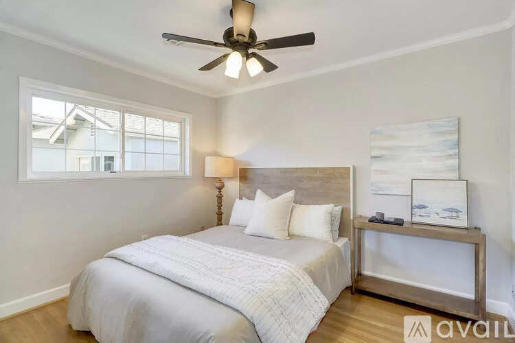 A bedroom with a large bed and a ceiling fan.