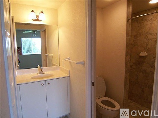A bathroom with a toilet, sink, and mirror.