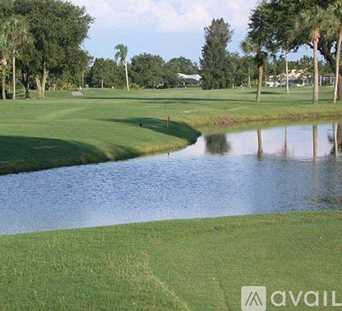 A golf course with a pond and trees in the background.