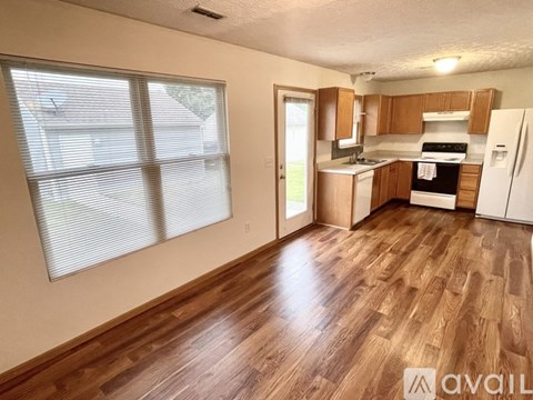 A kitchen with wooden floors and white appliances.
