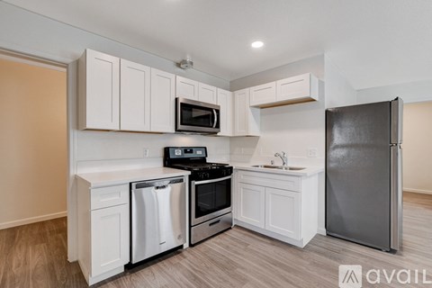 A kitchen with white cabinets and a black fridge.