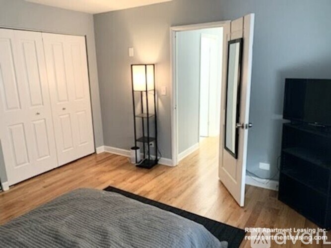 A bedroom with a bed, a lamp, and a TV.