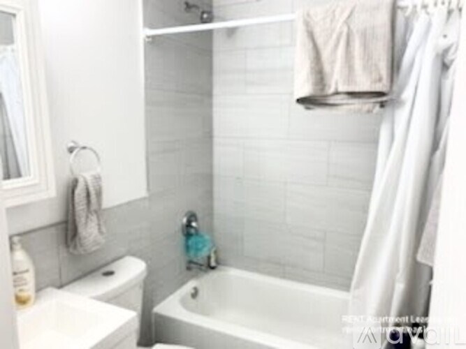 A white bathroom with a toilet, sink, and a white tub.