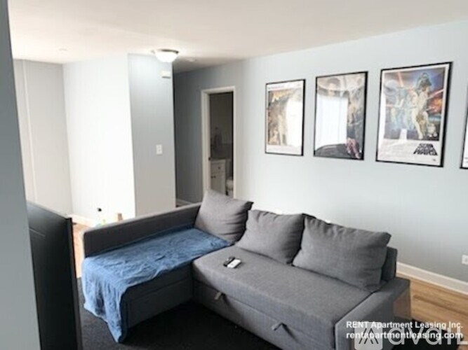 A bedroom with a bed, couch, and pictures on the wall.